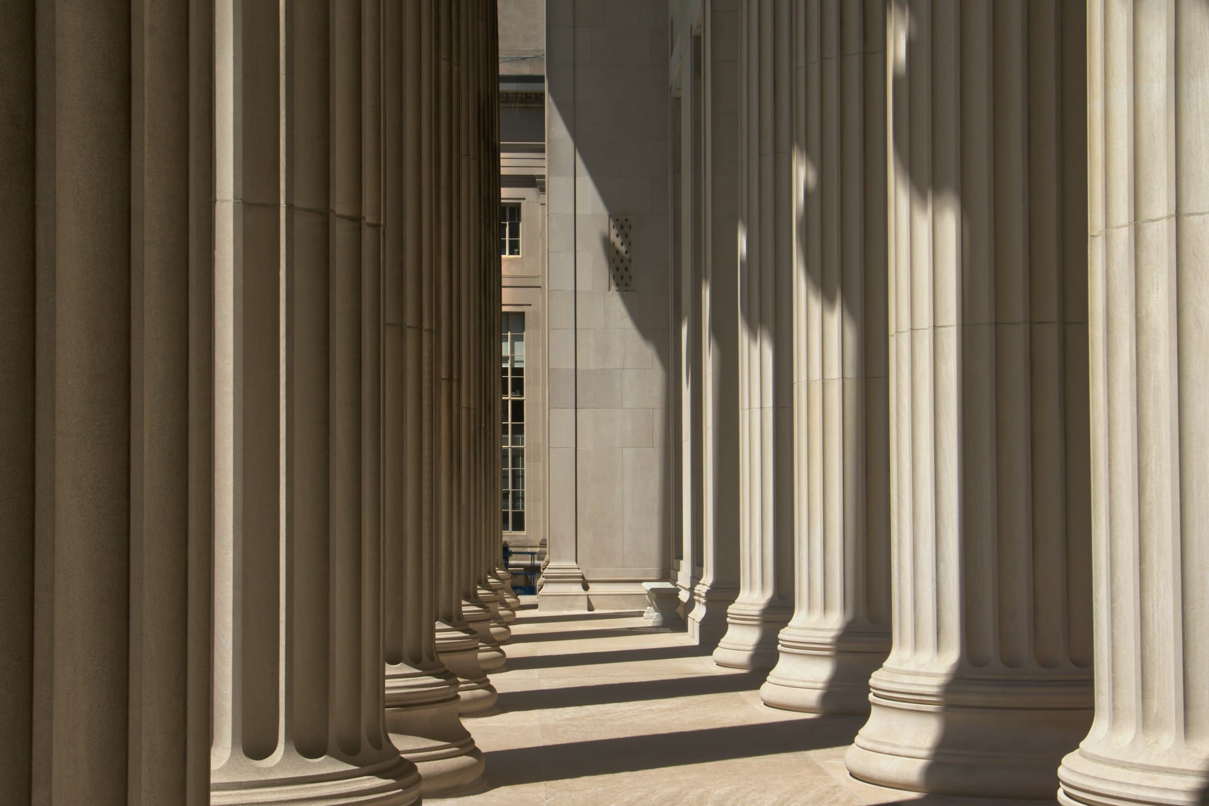 A row of fluted stone columns casting long shadows along a portico